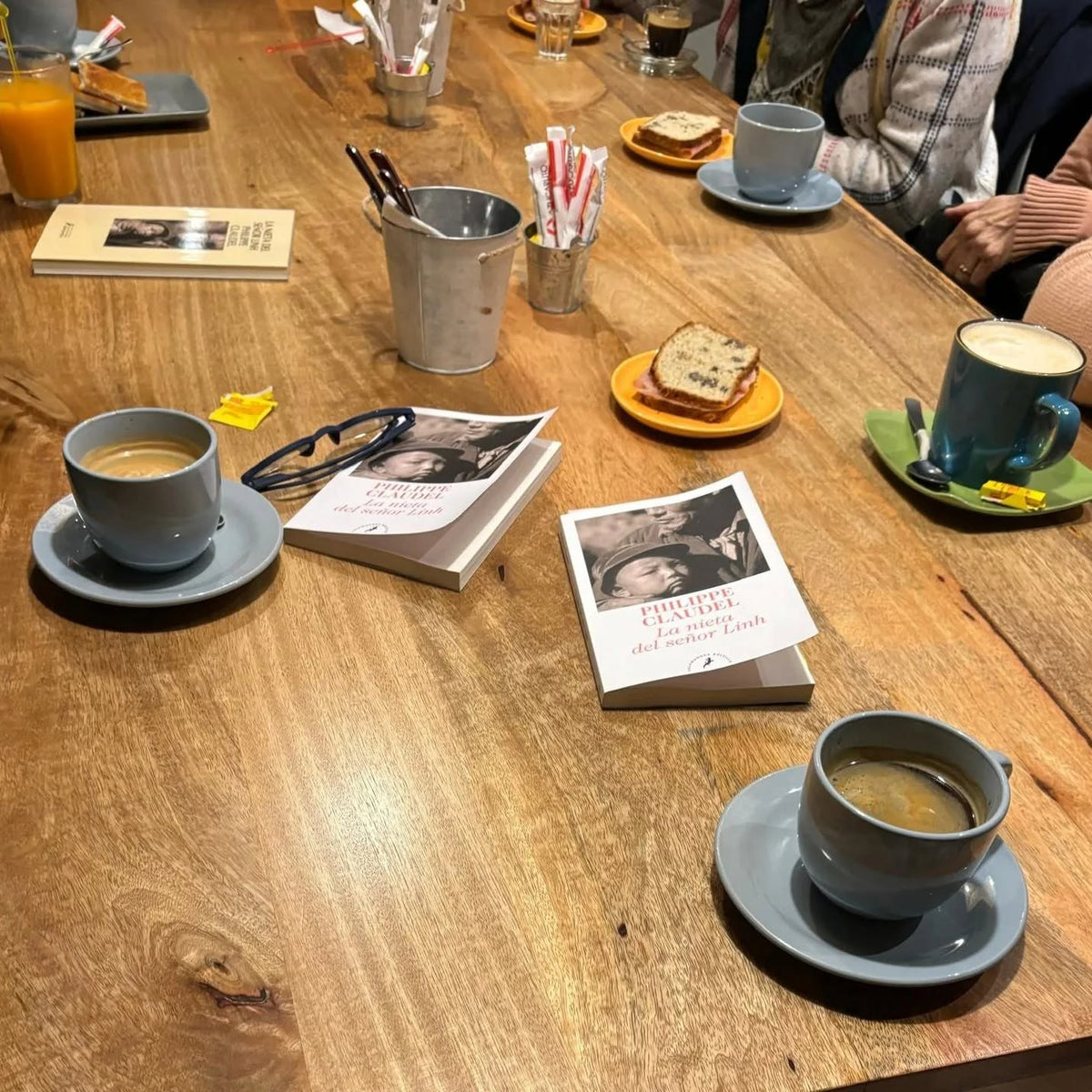 La mesa larga del Club de Lectores: cafés, budín y el libro del mes sobre la mesa.